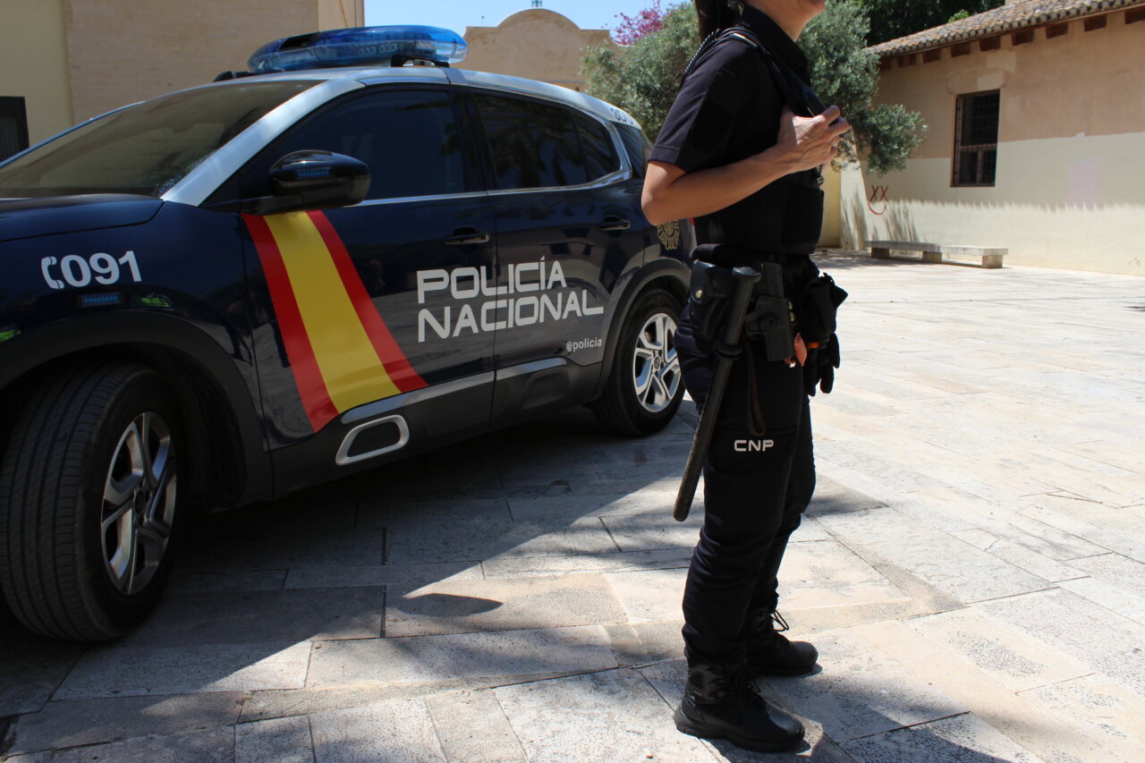 Agente de la Policía Nacional junto a un vehículo patrulla