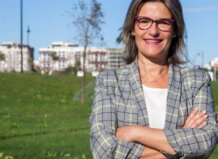 Mujer sonriente en un parque con edificios al fondo