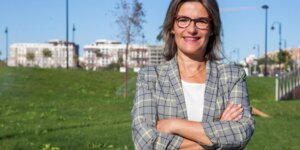 Mujer sonriente en un parque con edificios al fondo