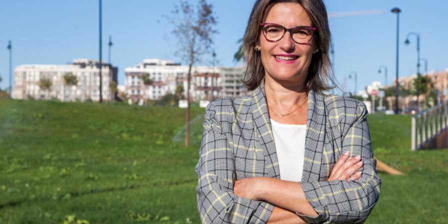 Mujer sonriente en un parque con edificios al fondo