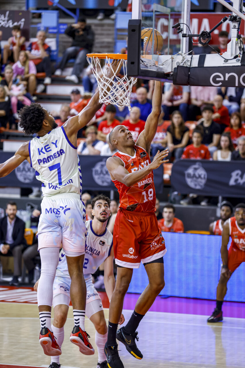 Jugador de Baxi Manresa anotando contra Valencia Basket en un partido emocionante.