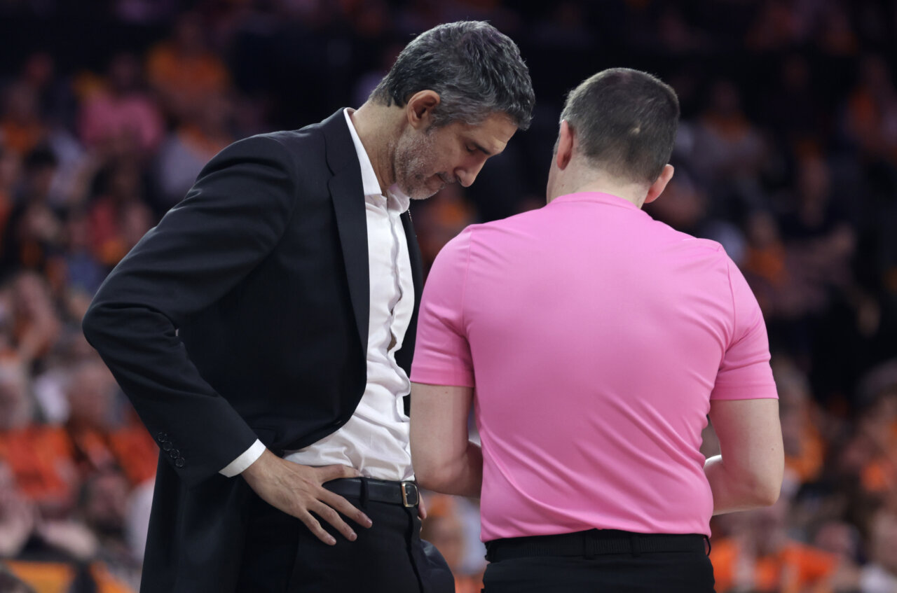 Rubén Burgos conversando con un árbitro durante un partido de baloncesto.