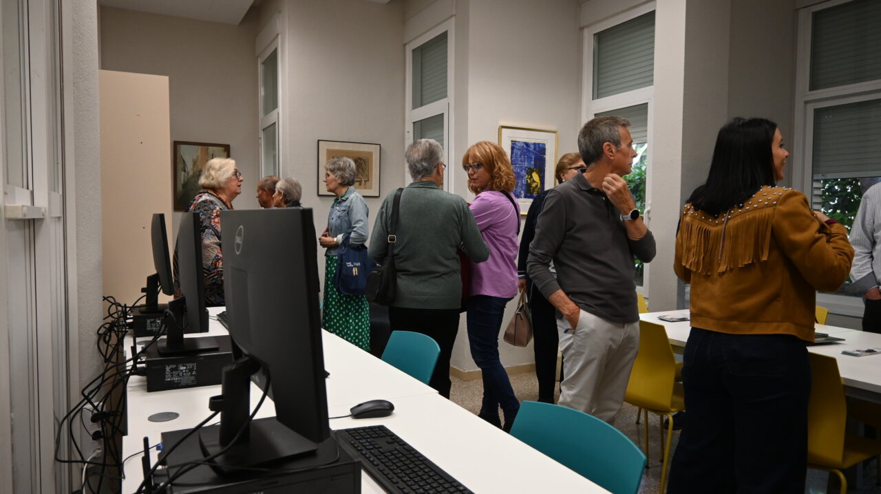 Personas mayores conversando en una sala de lectura moderna.