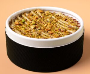 Tarta de queso gourmet con pistachos y galletas en un envase elegante