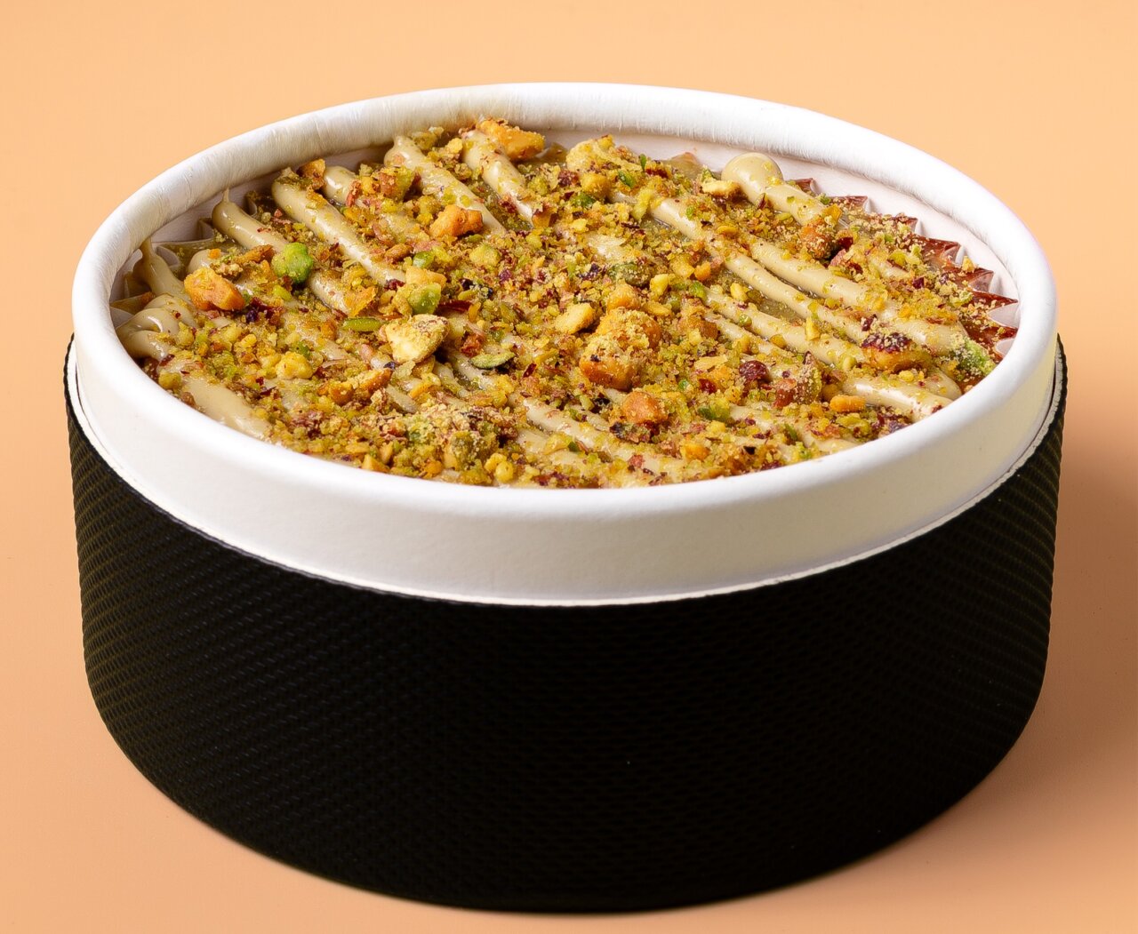 Tarta de queso gourmet con pistachos y galletas en un envase elegante