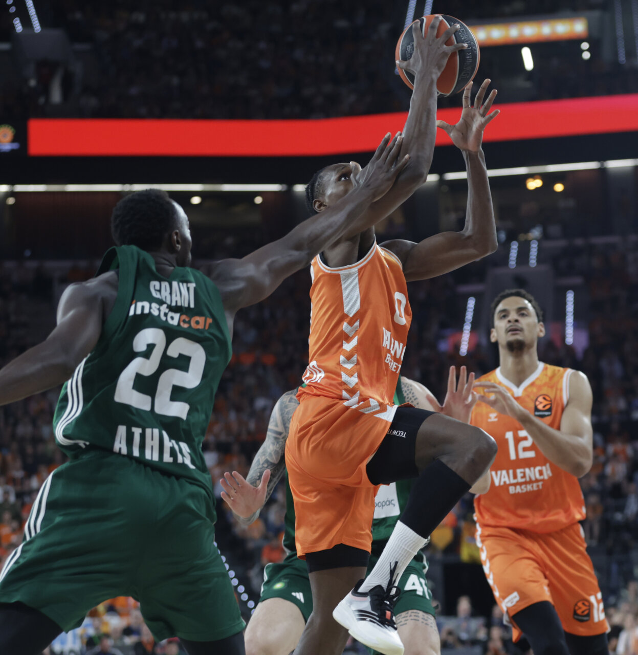 Jugador de Valencia Basket lanzando a canasta mientras es defendido por un rival