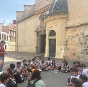 Grupo de escolares sentados en el suelo durante una visita cultural en Torrent