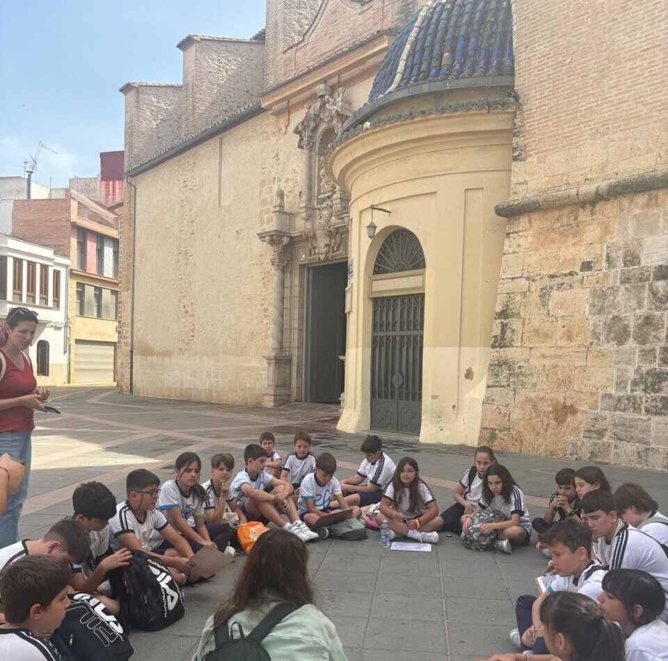 Grupo de escolares sentados en el suelo durante una visita cultural en Torrent