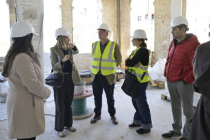 Grupo de personas en una obra de construcción con cascos y chalecos de seguridad
