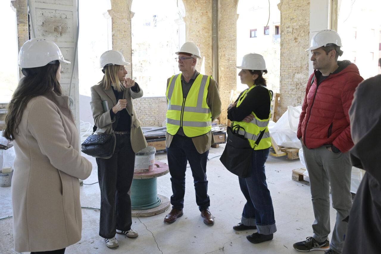 Grupo de personas en una obra de construcción con cascos y chalecos de seguridad