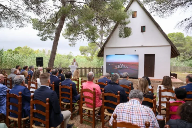 La Generalitat Valenciana e Iberdrola han anunciado la puesta en marcha de un proyecto estratégico para soterrar más de cinco kilómetros de líneas eléctricas aéreas en el Parque Natural de l’Albufera. La actuación, enmarcada en el Día Mundial del Medio Ambiente tras un pleno extraordinario del Consell, supondrá la retirada de 90 apoyos eléctricos en el entorno de El Saler y la Gola de Pujol, mitigando el impacto visual y paisajístico en este espacio protegido. El denominado Plan Albufera contará con una inversión de seis millones de euros por parte de la compañía eléctrica. El proyecto contempla la canalización subterránea de las líneas y el aprovechamiento de la superficie del nuevo trazado para la construcción de un carril ciclopeatonal. Asimismo, se desplegarán cinco nuevas líneas subterráneas para optimizar el suministro de energía en las pedanías del sur de València. Balance de 187 millones de euros en el entorno del parque Esta iniciativa complementa el balance inversor de la Generalitat, que ha movilizado más de 187 millones de euros en el último año y medio para la recuperación ambiental, hidráulica y de infraestructuras de l’Albufera y sus municipios ribereños tras los efectos de la dana. Entre las principales líneas de actuación ejecutadas y previstas destacan: Gestión de residuos y limpieza: Retirada de excedentes y sedimentos en municipios de la ribera (100 millones de euros), junto con la adecuación de acequias, compuertas y campos de arroz. Infraestructuras hidráulicas: Modernización de la Acequia Real del Júcar (25,7 millones de euros) y la ampliación de la estación depuradora de aguas residuales (EDAR) de Riba-roja (23,6 millones de euros). Conservación y dragados: Monitorización digital de la calidad del agua y una partida adicional de 15 millones de euros destinada a nuevos dragados selectivos. Gestión hídrica y recuperación de fauna Durante el encuentro se ha puesto en valor el comportamiento del humedal como zona de laminación natural de avenidas durante el episodio de inundaciones, un modelo de absorción de caudales que se proyecta replicar en futuros parques inundables de la Comunitat Valenciana a través de 72 kilómetros de corredores verdes. Por otra parte, la administración autonómica ha refrendado el primer Pacto del Agua por l’Albufera con los regantes de los ríos Júcar y Turia para asegurar las aportaciones hídricas regulares. El acto institucional ha concluido en el embarcadero de La Granja con la liberación de varias especies de ánades recuperadas por este centro de fauna, que ha atendido a más de 9.300 ejemplares durante el último año.
