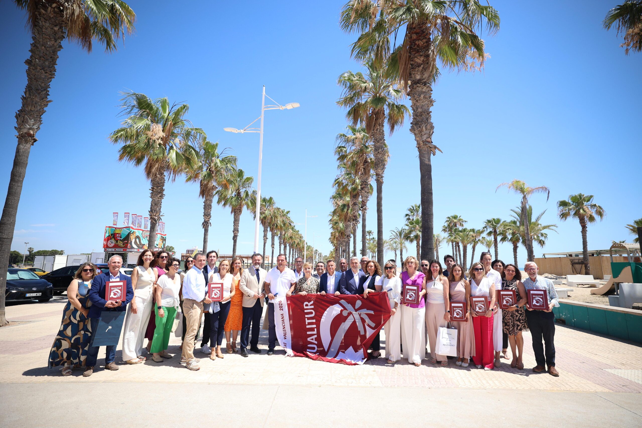 Las playas de Alboraya, La Pobla de Farnals, El Puig y Puçol lucirán este verano la Bandera Qualitur 2026, el distintivo concedido por Turisme Comunitat Valenciana a los municipios que acreditan estándares certificados en calidad, medio ambiente y accesibilidad. En total, la Generalitat ha reconocido a 206 playas y calas de 40 municipios de la Comunitat Valenciana.
La distinción reconoce el esfuerzo de los ayuntamientos por ofrecer playas con aguas limpias, arenas cuidadas, servicios higiénicos, medidas de vigilancia, zonas de esparcimiento y ocio, protección ambiental y accesibilidad universal.
La consellera de Industria, Turismo, Innovación y Comercio, Marián Cano, ha entregado este lunes las banderas en un acto celebrado en Burriana, acompañada por el alcalde de la localidad, Jorge Monferrer, y por el secretario autonómico de Turismo, José Manuel Camarero.
Durante su intervención, Cano ha afirmado que “hoy no hemos entregado únicamente unas banderas; hemos reconocido el esfuerzo de los municipios que trabajan durante todo el año para ofrecer playas y calas en las mejores condiciones de calidad, seguridad, sostenibilidad ambiental y accesibilidad”.
La consellera ha defendido que la Bandera Qualitur evidencia la capacidad de la Comunitat Valenciana para situarse a la vanguardia de la excelencia turística y ha subrayado que este distintivo es “la seña de identidad de esa excelencia”.
En la provincia de Valencia, la Bandera Qualitur ondeará este verano en 17 municipios costeros: Alboraya, Bellreguard, Canet d’En Berenguer, Daimús, Cullera, Gandia, Miramar, Oliva, Piles, La Pobla de Farnals, El Puig de Santa María, Puçol, Sagunto, Sueca, Tavernes de la Valldigna, València y Xeraco.
La provincia de Valencia es la que cuenta con mayor número de municipios distinguidos, con 65 certificados distribuidos en 44 playas. En número de certificados destacan Cullera, con 12; Sagunto, con 9; y València, con 7. En número de playas certificadas sobresalen Cullera, con 8, y Oliva, con 6.
En el conjunto de la Comunitat Valenciana, Turisme ha concedido la Bandera Qualitur a 206 playas y calas que reúnen alguno de los certificados reconocidos en materia de calidad, gestión medioambiental o accesibilidad. En total, se han contabilizado 143 certificados distribuidos entre los 40 municipios galardonados.
Los modelos de excelencia reconocidos son la ISO 9001 y la Q Calidad Turística en materia de calidad; la ISO 14001, el Reglamento EMAS y la S de Sostenibilidad en gestión medioambiental; y la Norma UNE 170001 en accesibilidad.
De los 143 certificados concedidos, el 55% corresponde a sistemas de calidad, el 39,16% a gestión medioambiental y el 6,29% a accesibilidad.
Por provincias, Castellón suma 11 municipios reconocidos, con 35 certificados repartidos en 70 playas y calas. Alicante cuenta con 12 municipios galardonados, 43 certificados y 92 playas y calas, lo que la sitúa como la provincia con mayor número de playas reconocidas.