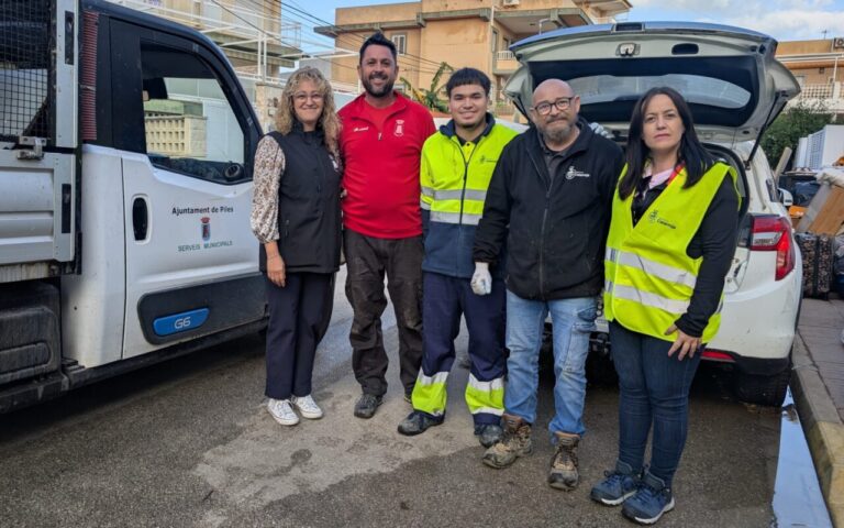 Cinco personas junto a un camión municipal de Piles y un coche con el maletero abierto
