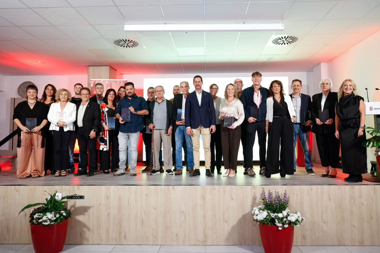 Grupo de personas posa en un escenario con placas de reconocimiento.