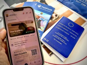 Móvil con la aplicación PetFirst junto a un pasaporte europeo para animales de compañía