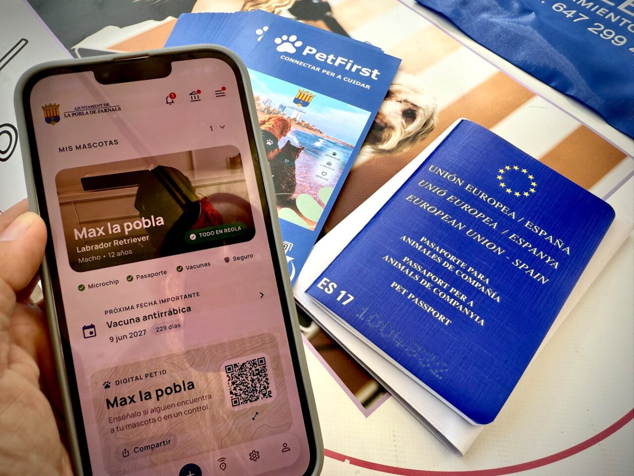 Móvil con la aplicación PetFirst junto a un pasaporte europeo para animales de compañía